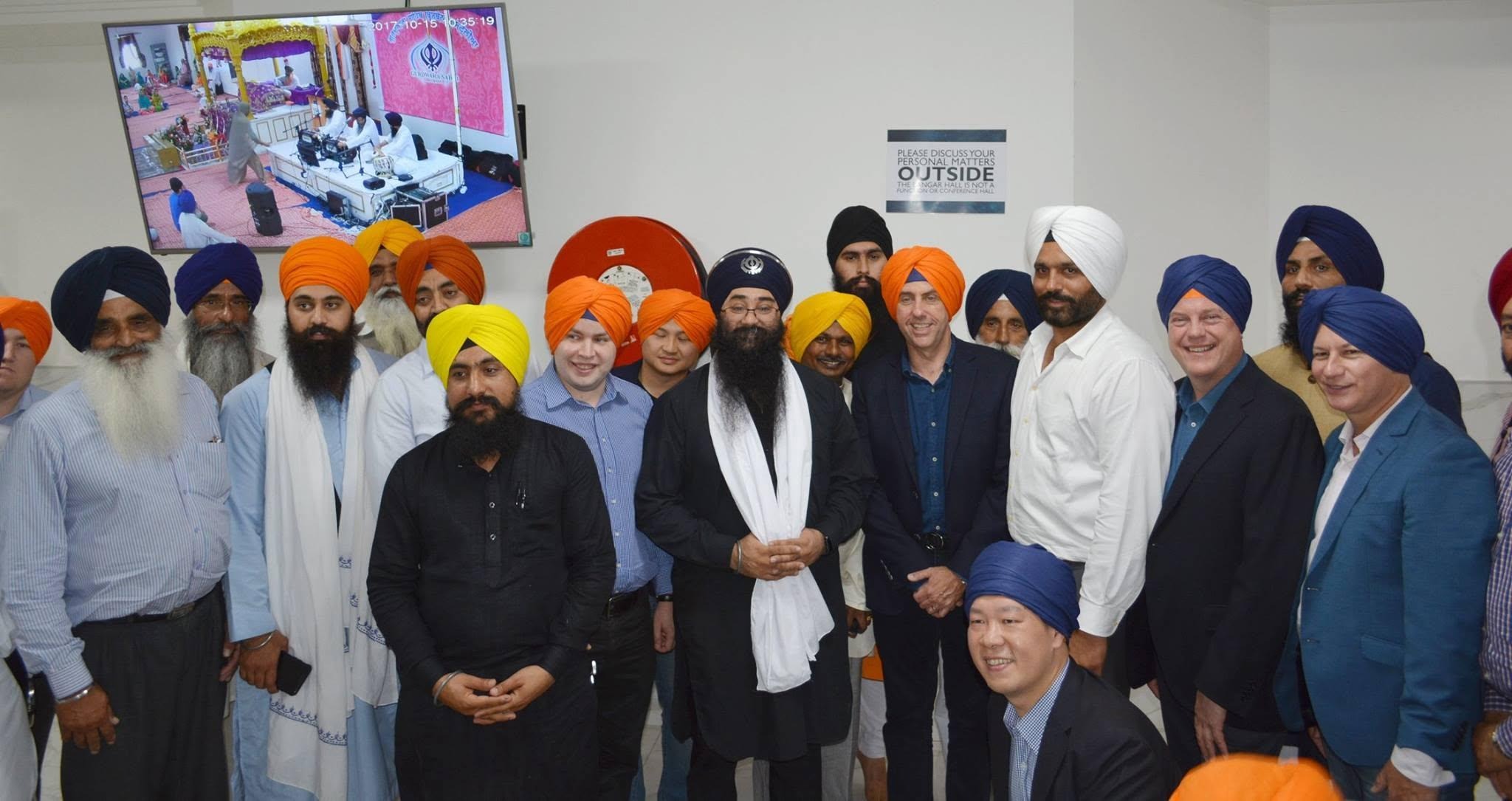 Community leaders and guests wearing turbans with the sangat in the langar hall